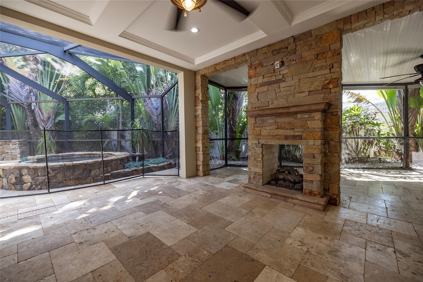 Entertain with covered and screened travertine patio with gas fireplace