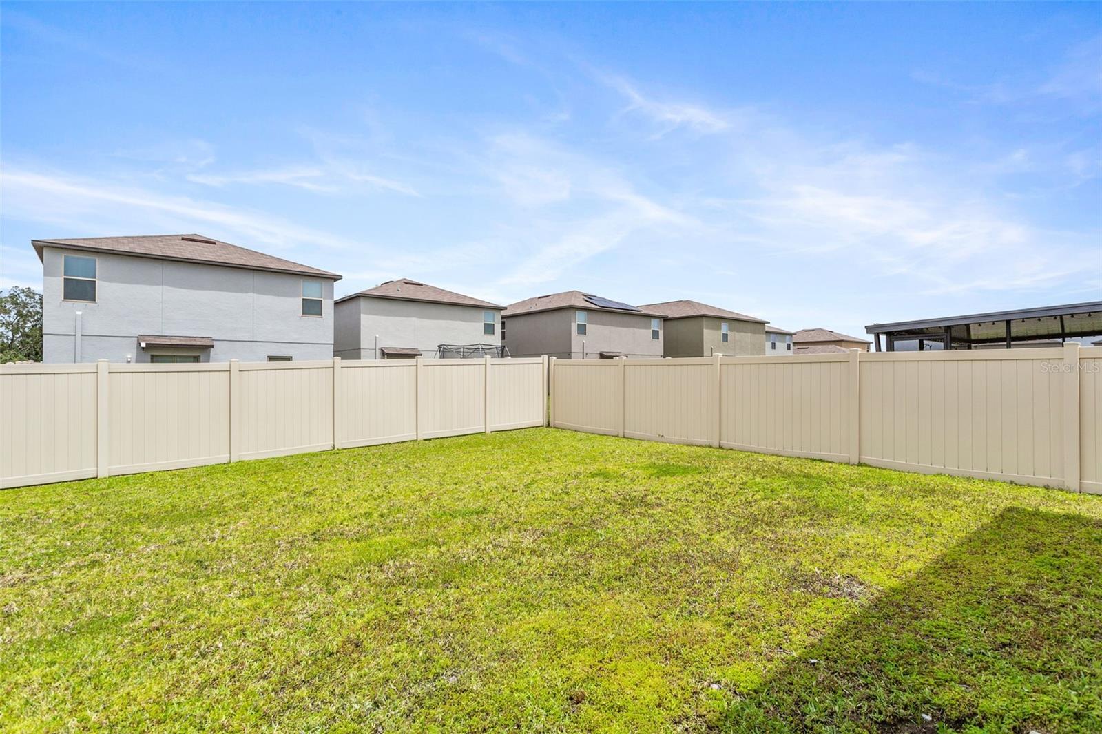 large partially fenced backyard with sprinkler system