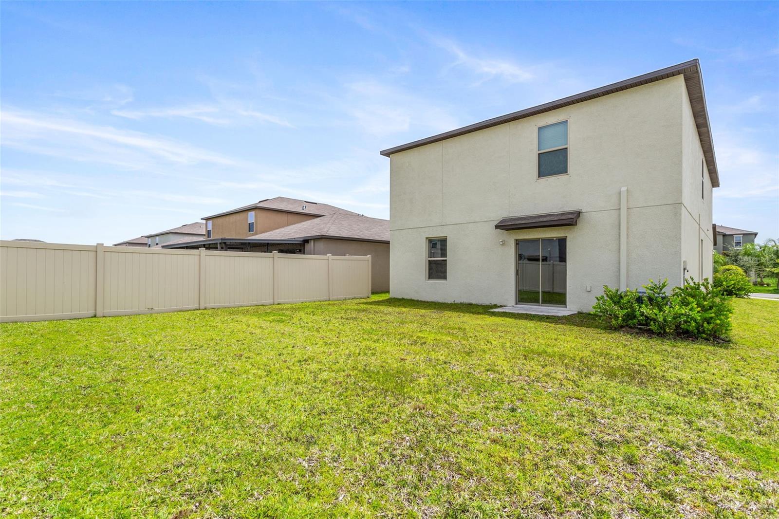 large partially fenced backyard with sprinkler system