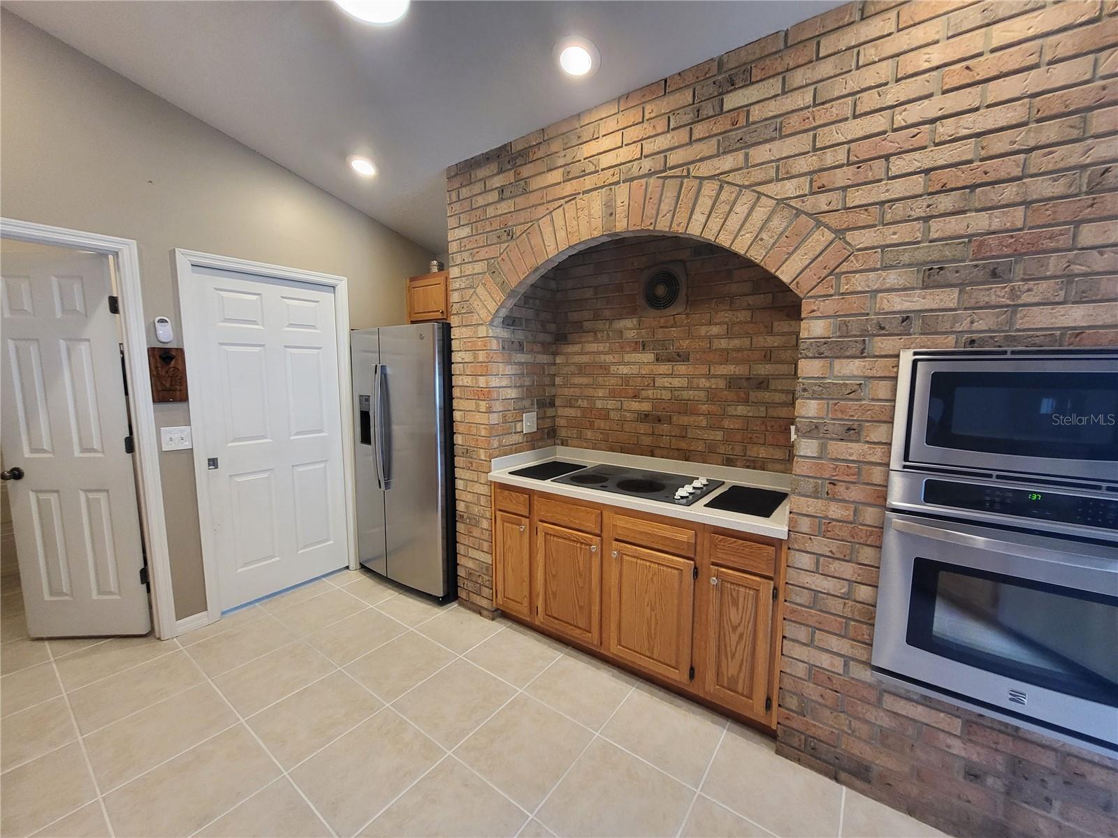 Stainless steel appliances surround the brick hearth style cooking station.