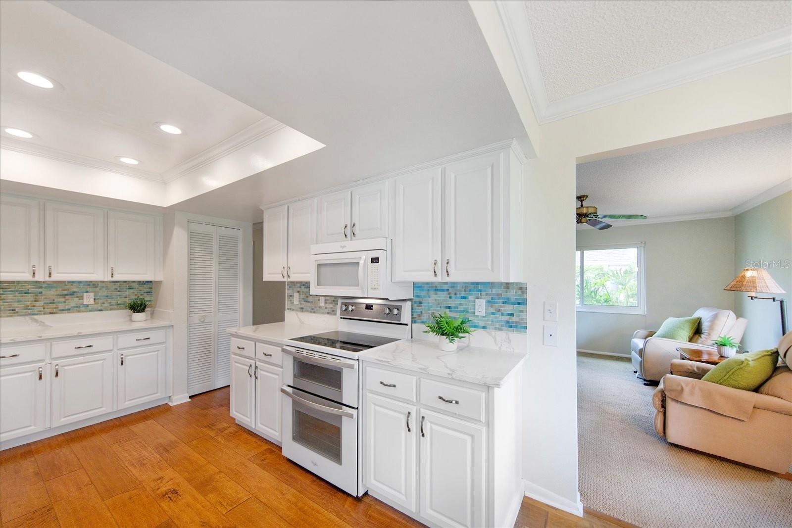 White panel cabinets & quartz counters perfectly finished with splash walls in a sand, gulf, & sea glass medley of tile~