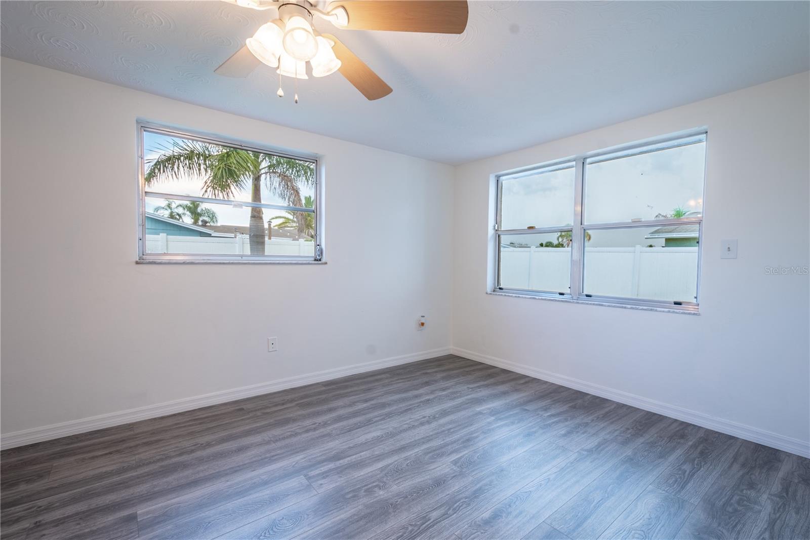 The primary bedroom features wood laminate flooring and a ceiling fan with light kit.