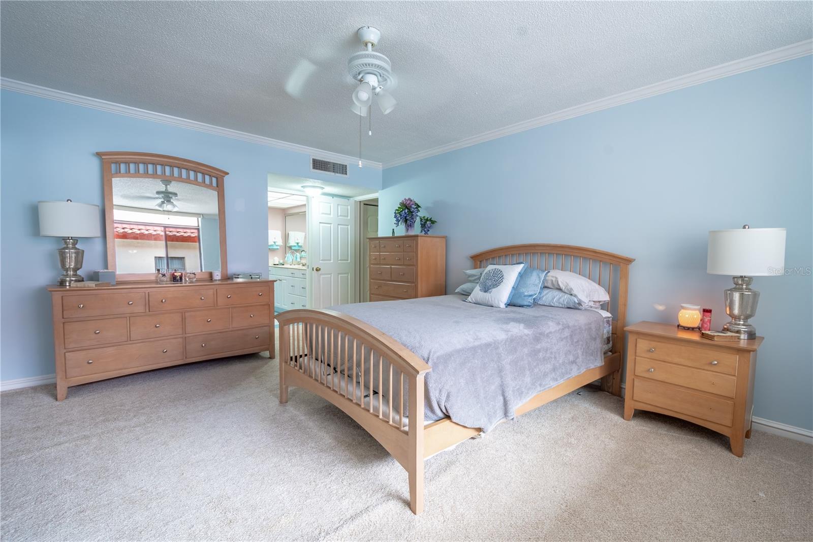 Bedroom two features neutral tone carpet, crown molding, a ceiling fan and a built-in closet.