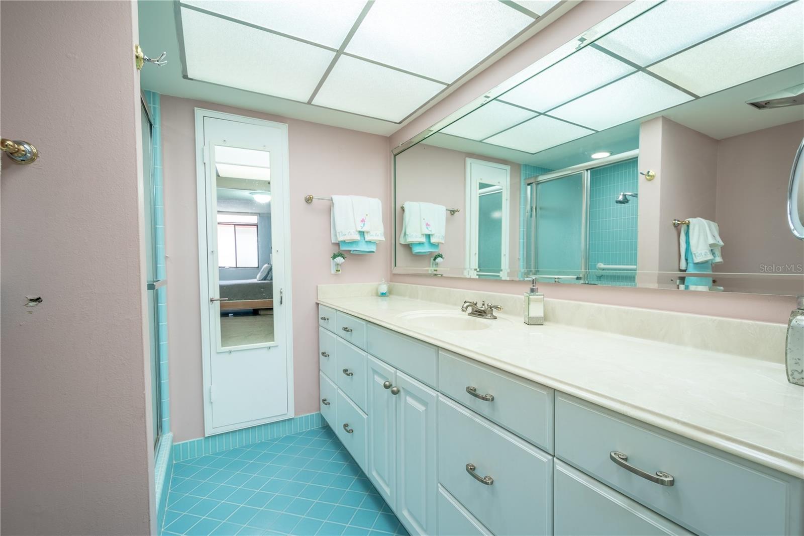 The primary bathroom features a mirrored vanity with storage, a floor to ceiling medicine cabinet, ceramic tile flooring and a walk-in shower.