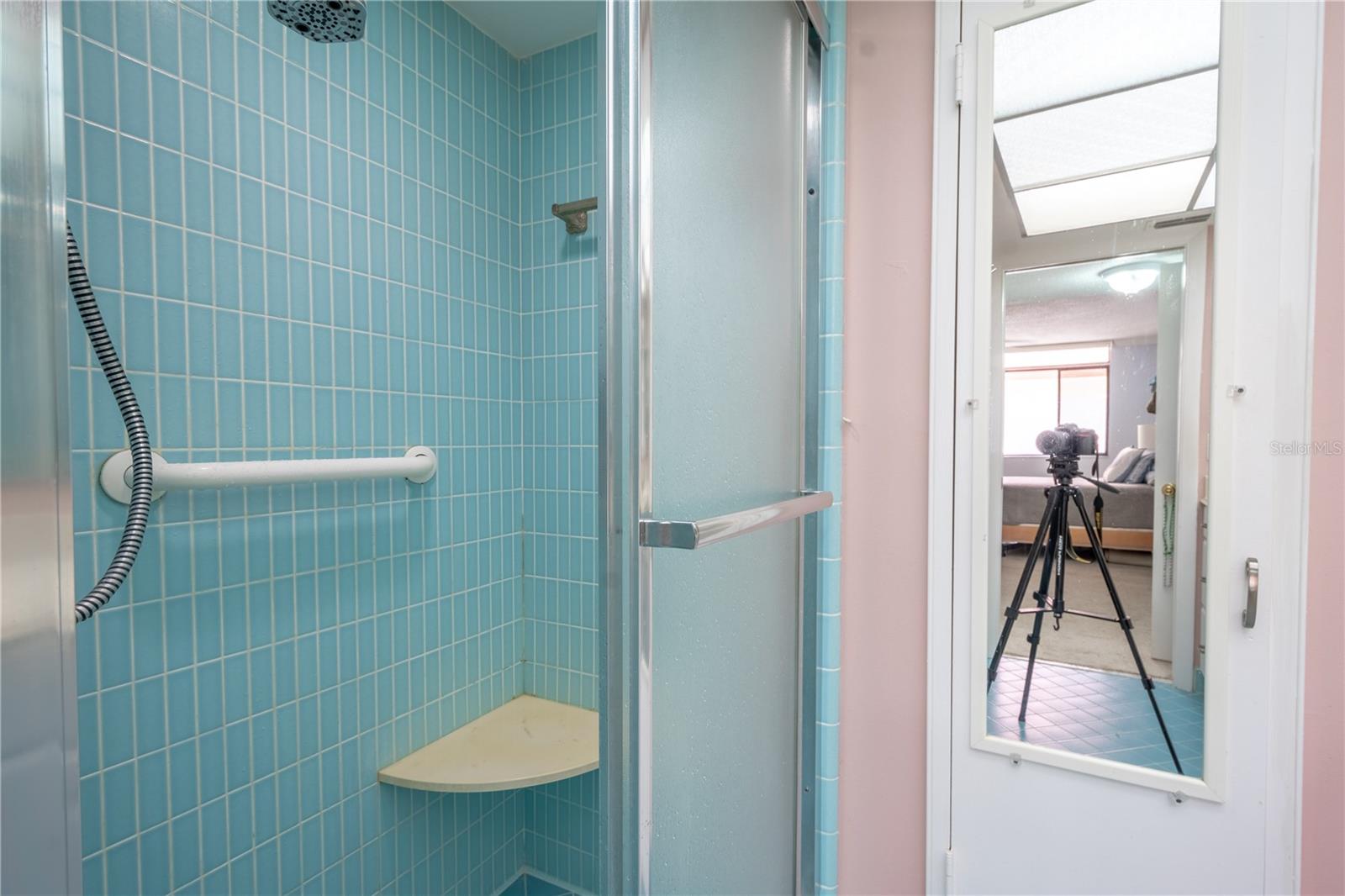 The primary bathroom features a tiled walk-in shower with grab bar and built-in bench.