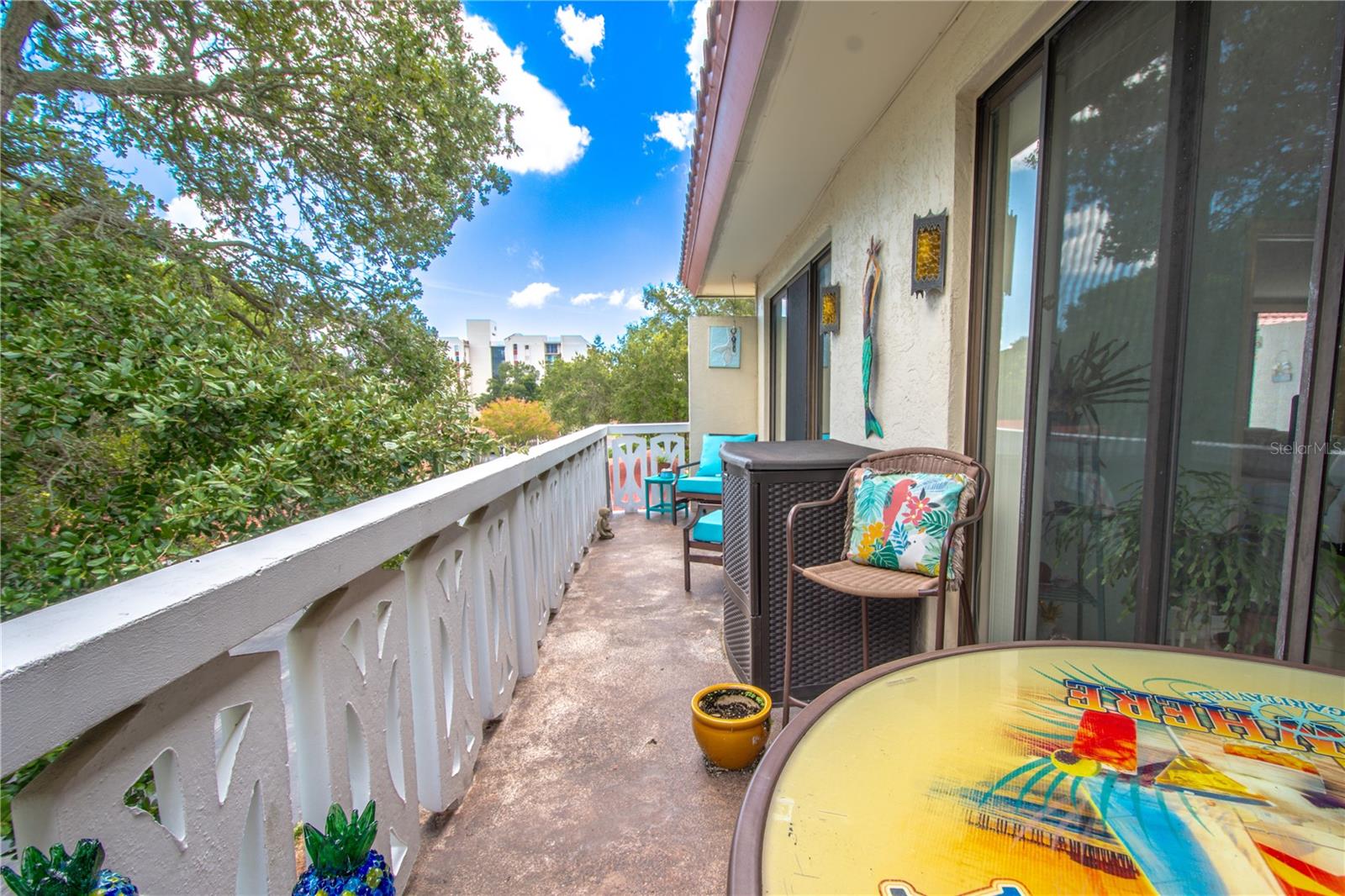 Balcony two stretches the width of the condo , shaded by the tree tops.