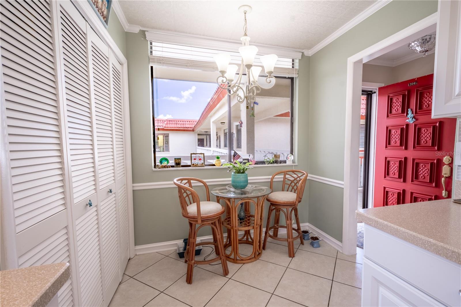 The kitchen features a cozy breakfast nook beneath a chandelier. Shutters doors enclose a closet pantry.