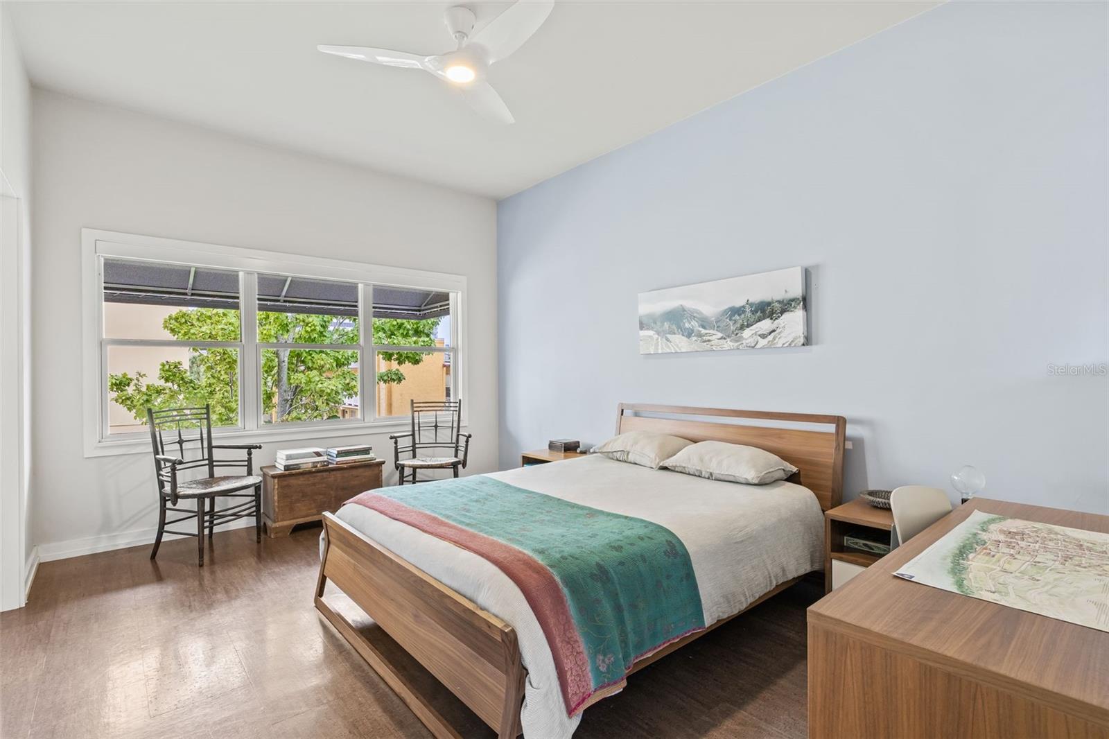 The easy to clean cork floors that go throughout the home - this is the spacious primary bedroom with large windows that let the sun shine in!