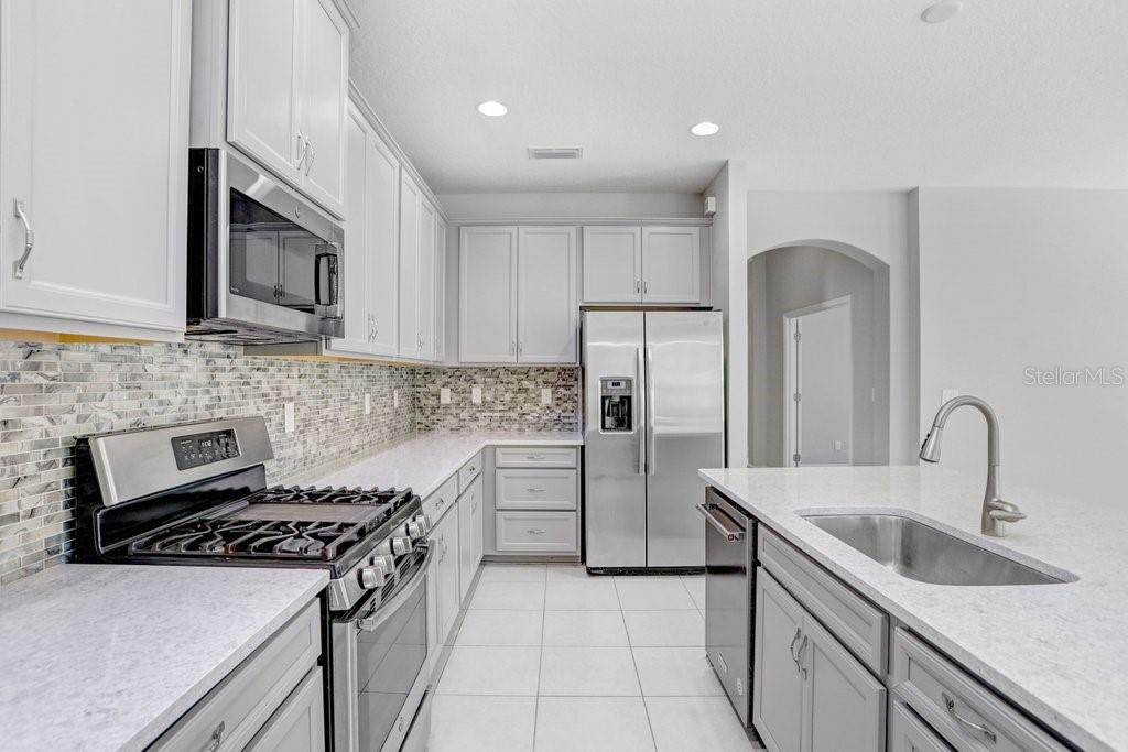 Kitchen with 42" cabinets, quarter countertops, stainless steel appliances, and back splash