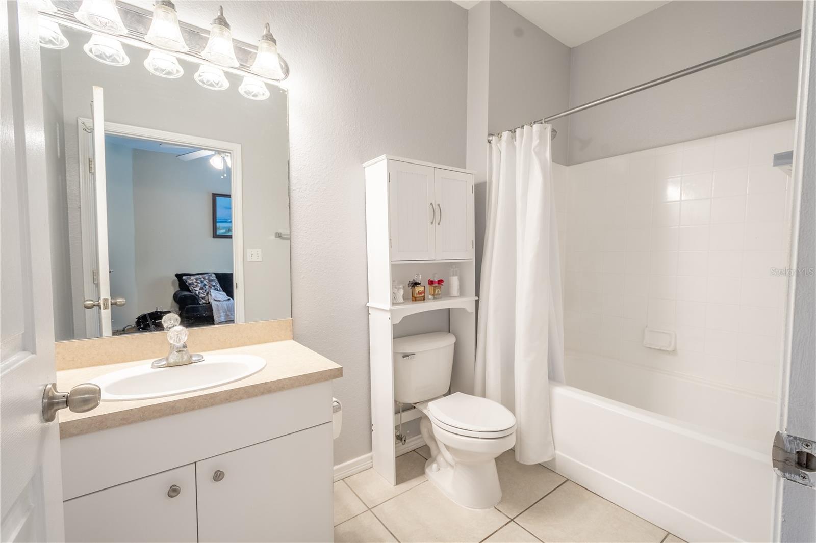 The primary ensuite features a ceramic tile floor, tub with shower, and a mirrored vanity with stirage and down light fixture.