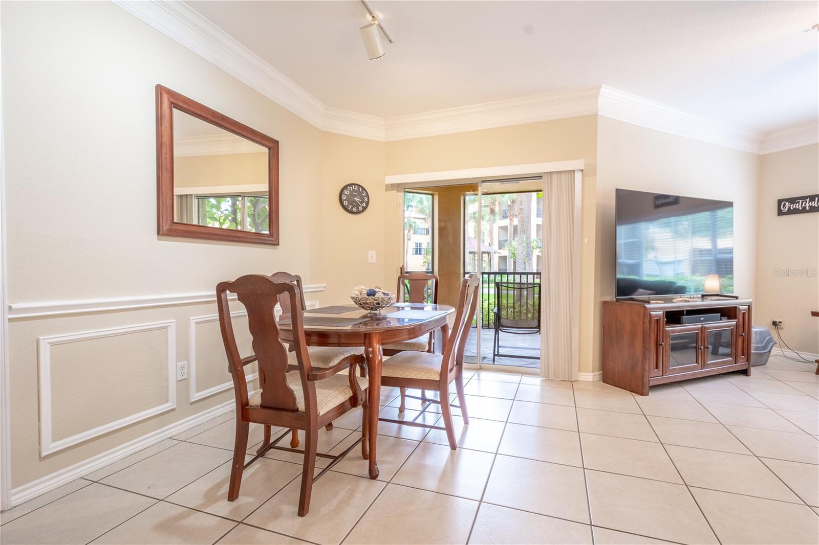 The dining area features decorative molding and chair rail, ceramic tile flooring and a track light fixture. It also features sliding glass doors to the screen in patio.