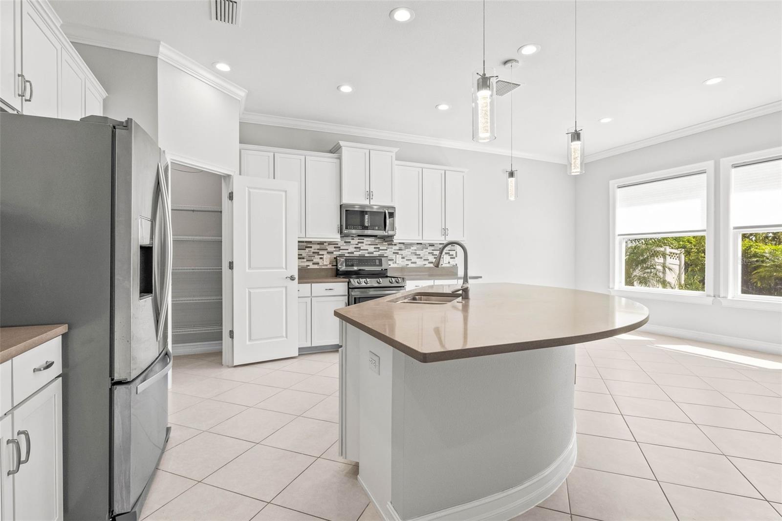 Kitchen area has stainless steel appliances, quartz countertops, closet pantry, and seating in the dinette and the island.