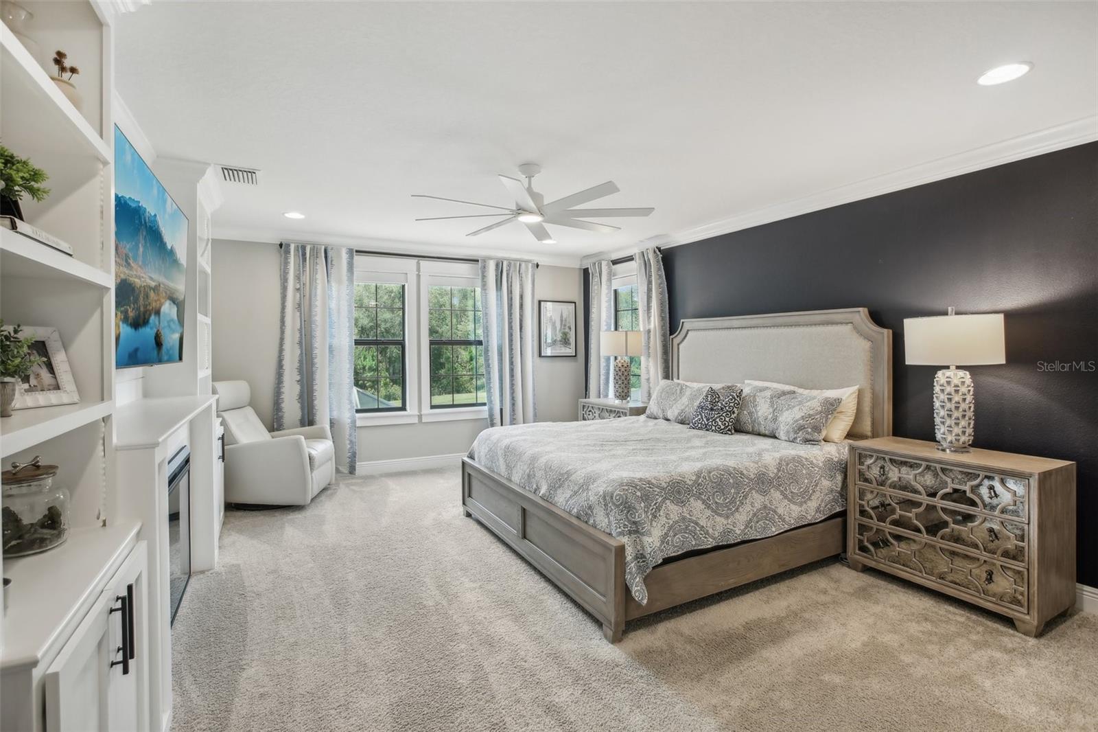 Primary bedroom with custom built in wall shelving/fireplace