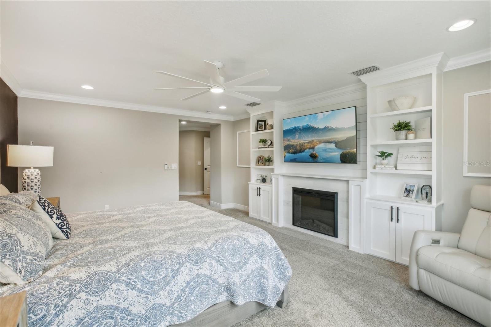 Primary bedroom with custom built in wall shelving/fireplace