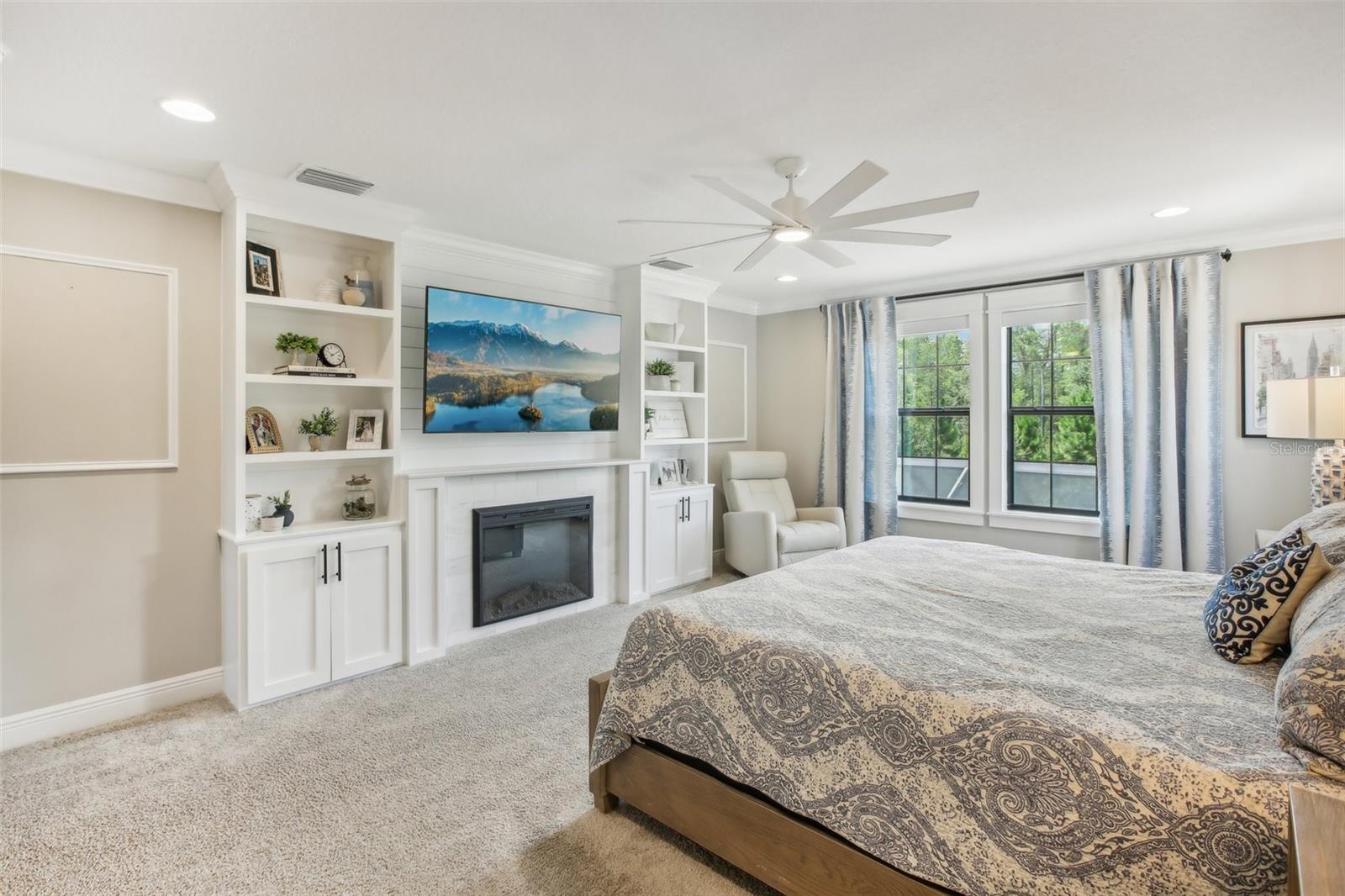 Primary bedroom with custom built in wall shelving/fireplace