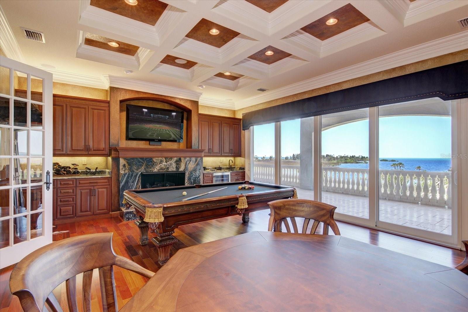 The Billard Room with gas fireplace covered in granite, built in solid cherry cabinets, granite countertops, wet bar, & built in refrigerator