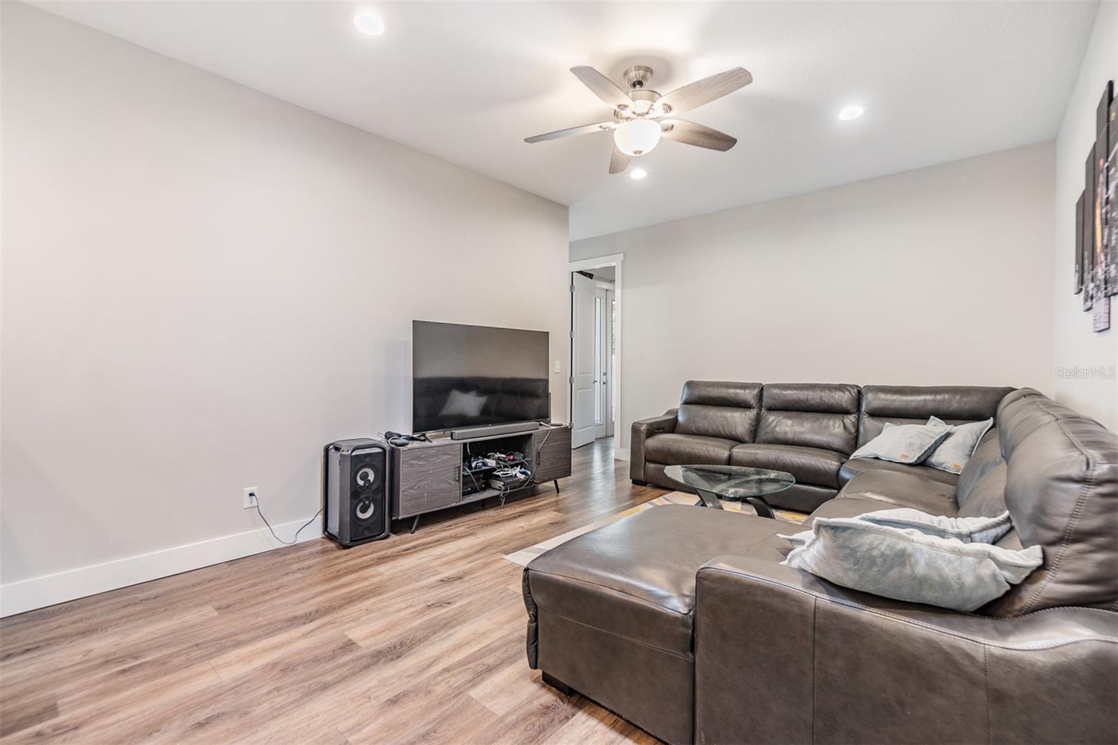 Family room, just off of the kitchen, ceiling fan, 5 inch baseboards and high ceilings.