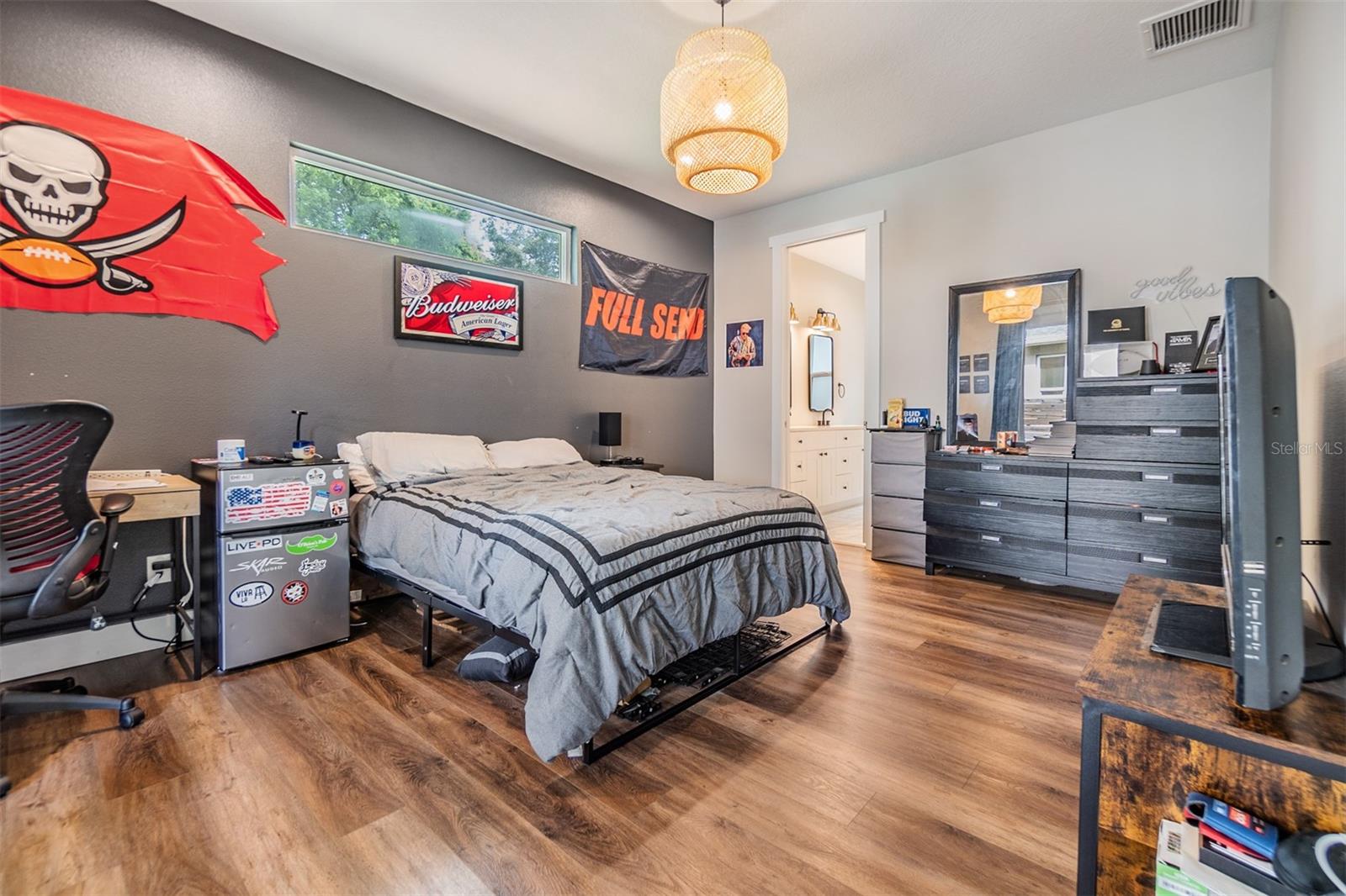 Primary Bedroom with provate bathroom, lots of natural light with the transom window, wood flooring and updated light fixture.