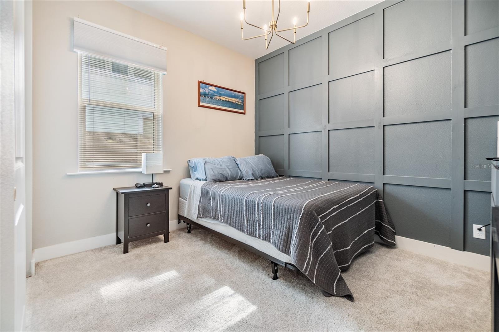 Guest bedroom with accent wall and updated light fixture