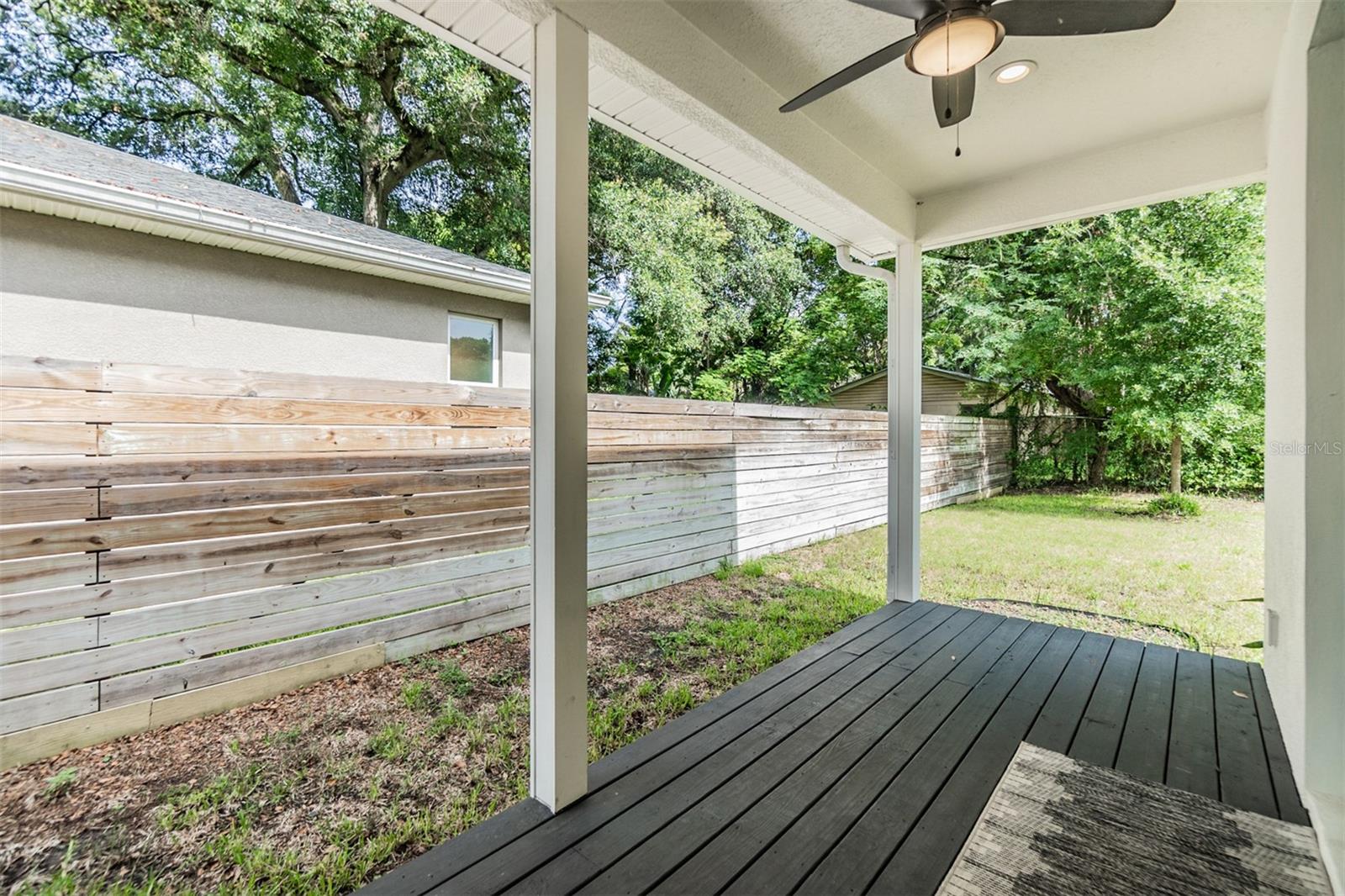 Backyard covered porch with ceiling fan/light.