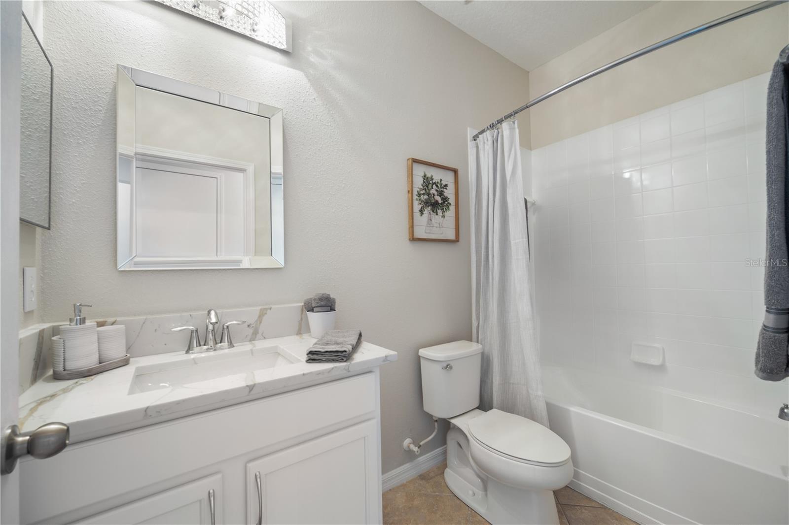 Guest bath 1, level 4 quartz countertops, white and bright with new light fixtures and mirror