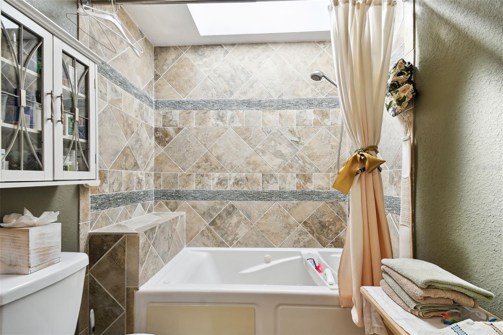 Remodeled primary bathroom with jet tub, skylight, double vanity