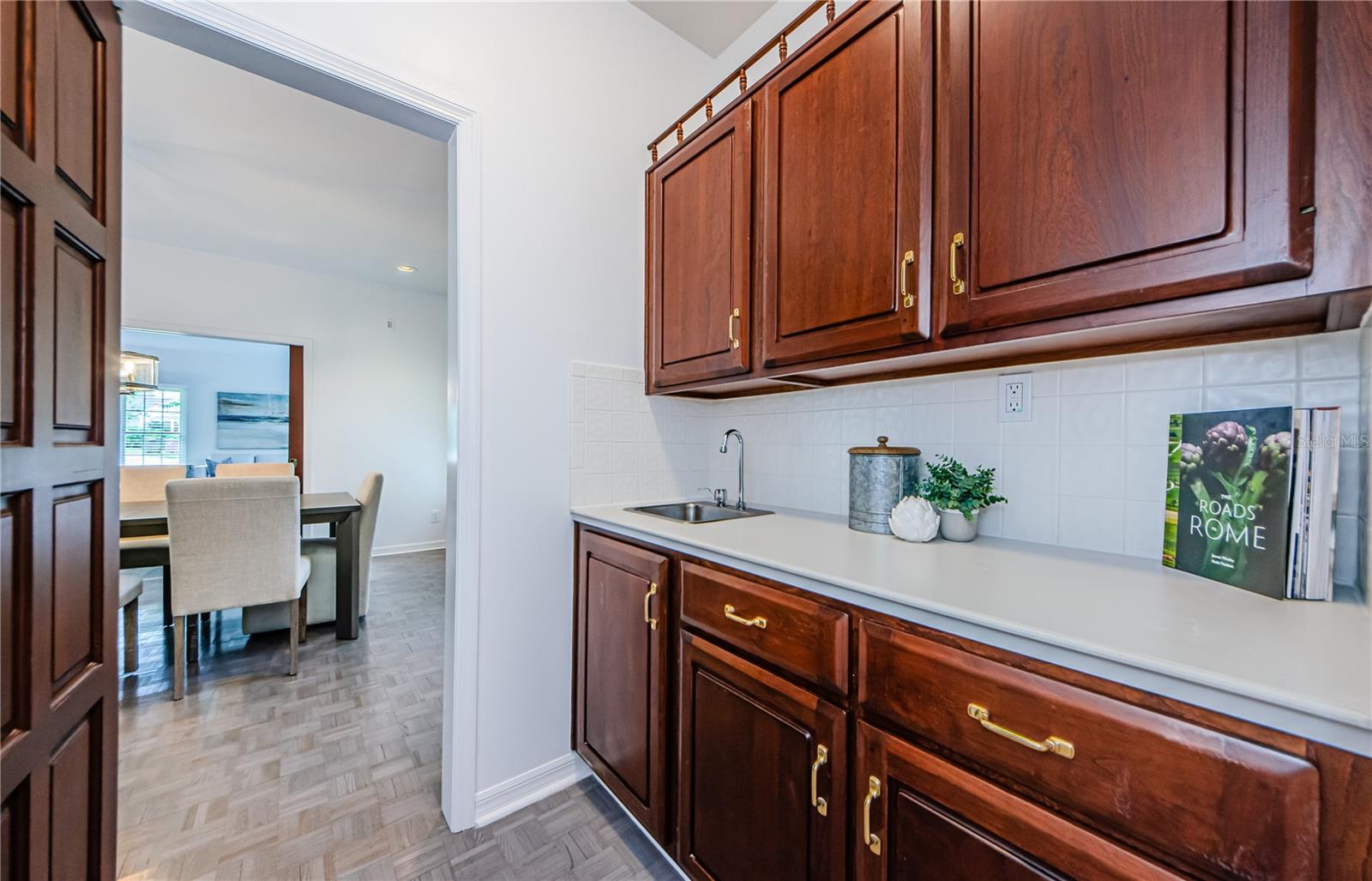 Rich cherry wood cabinets and Corian counters with sink, back splash in this beautiful Butler's Pantry with large storage closet.