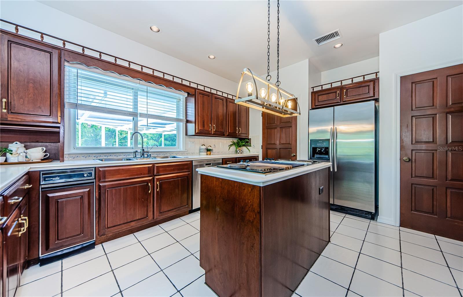 Kitchen with cherry wood cabinets, large window over kitchen sink, separate, large laundry room behind door to left of refrigerator, and large pantry behind door on right side.