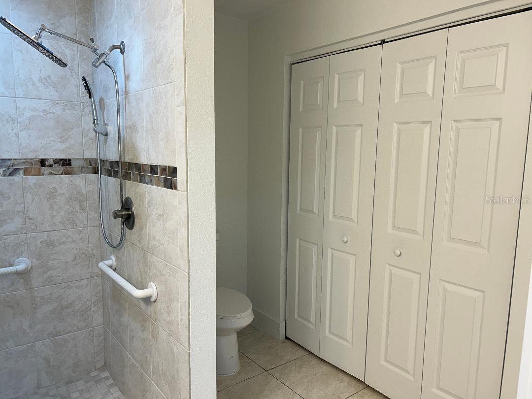 Master shower sloped, wide entry with assist bars toilet/closet