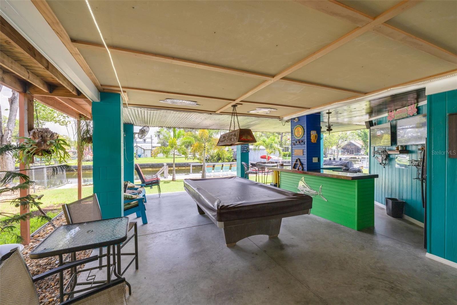 Carport under building parking with pool table and built in bar / entertaining area