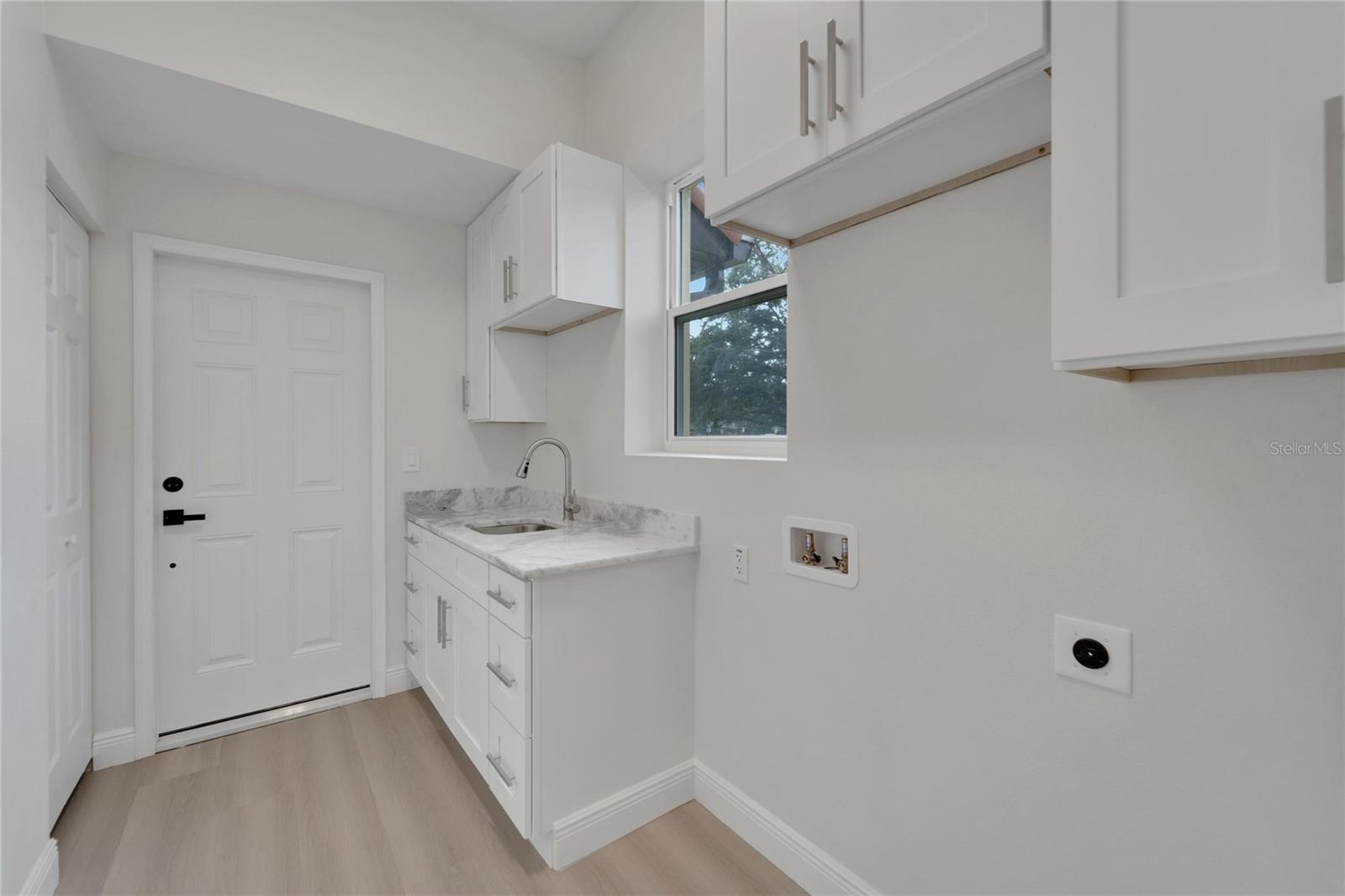 Laundry room leading to garage - complete with custom sink & matching soft-close cabinets and drawers