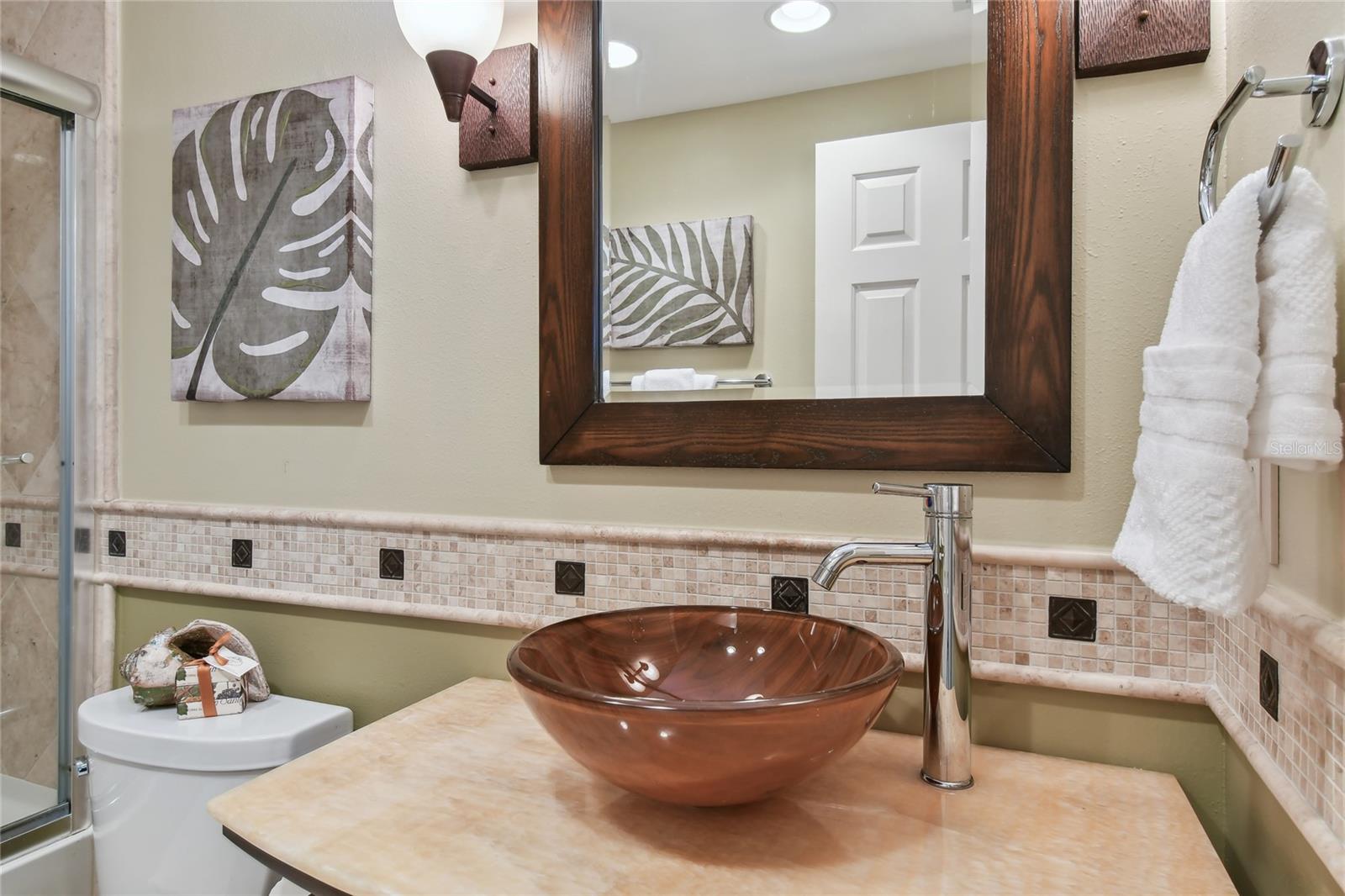 A custom Guest Bath features marble and glass vessel sink