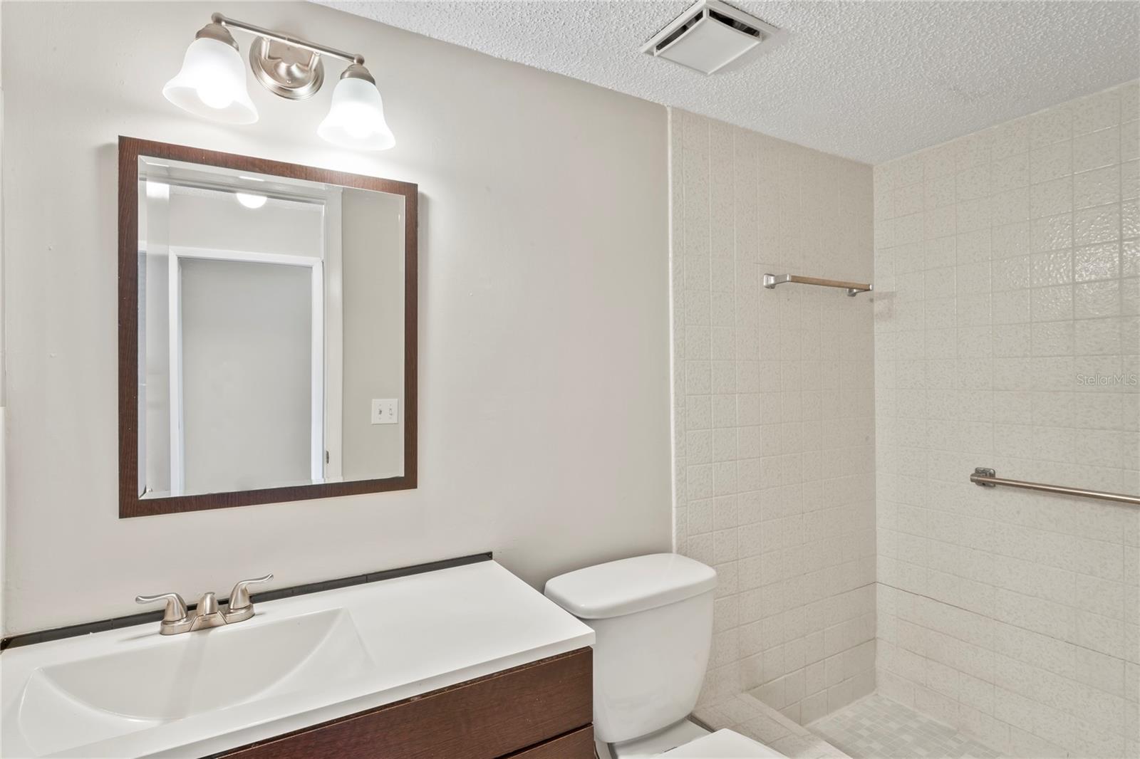 Guest bathroom features shower, single vanity and vent.