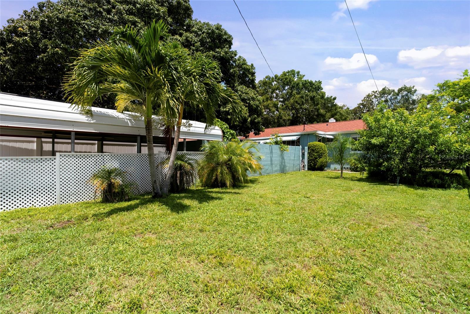 Outdoor space with yard that has a double entry gate and large covered parking.