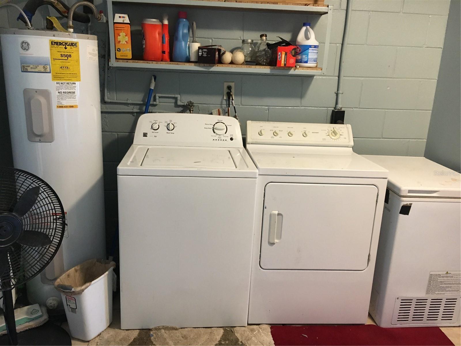 Laundry room showing water heater, washer, dryer, and small freezer