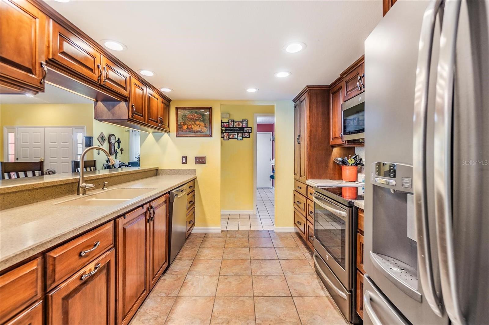 Beautifully updated kitchen with new stainless steel appliances, Corian countertops, recessed lighting, breakfast bar, and large walk-in pantry