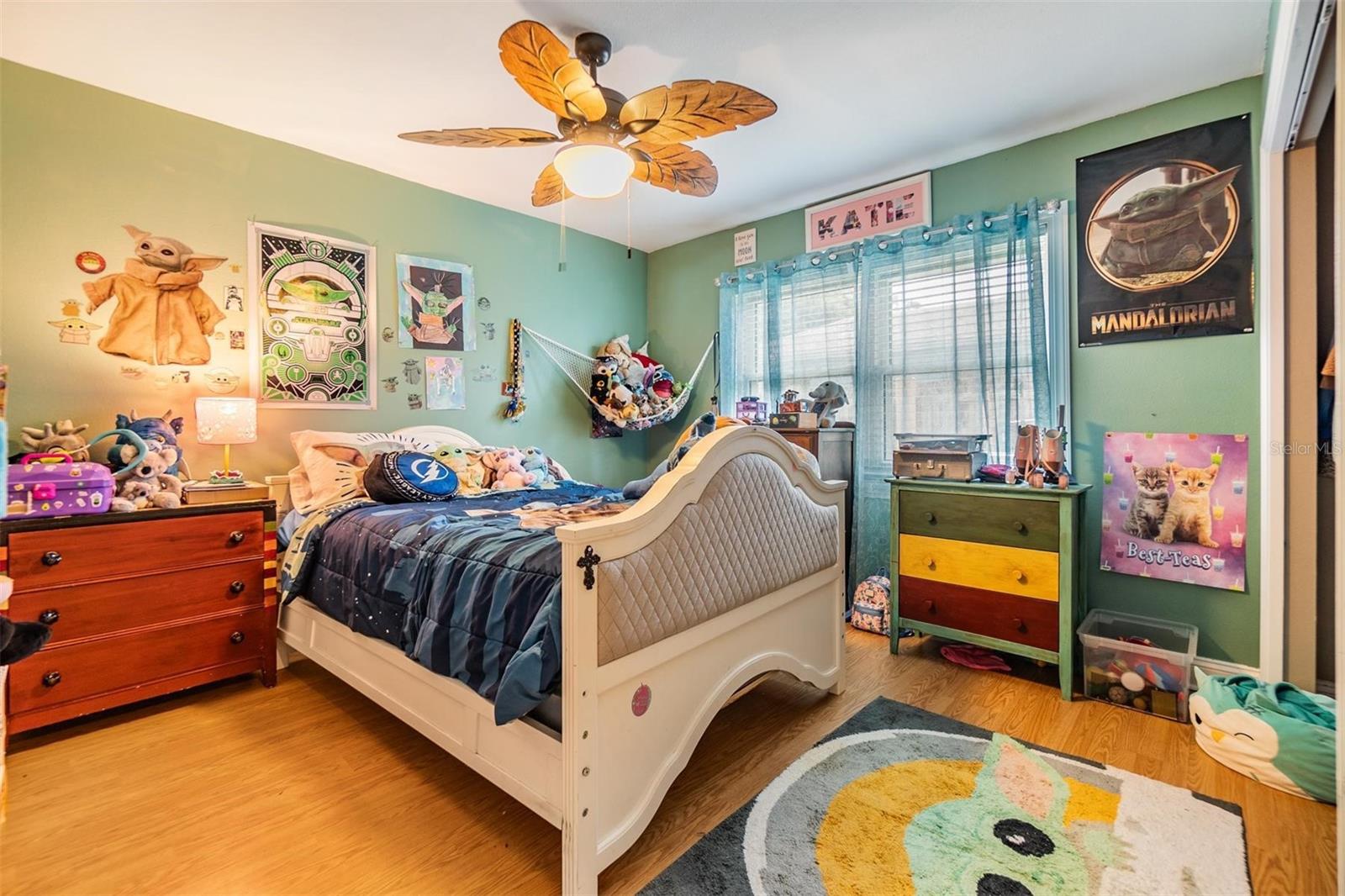 Third bedroom with wall closet, laminate floors, decorative fan and wall closet