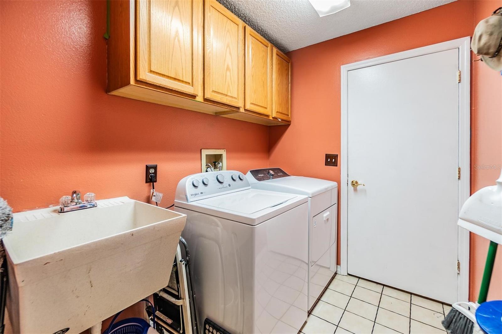 Laundry room with storage cabinets utility sink and garage entry