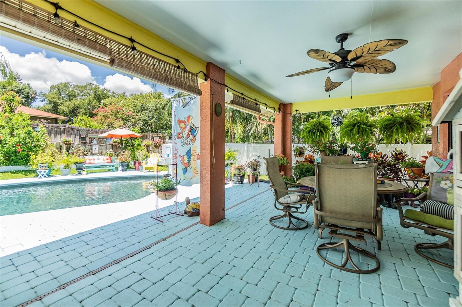 Covered outdoor seating area by pool with sunshades and decorative fan