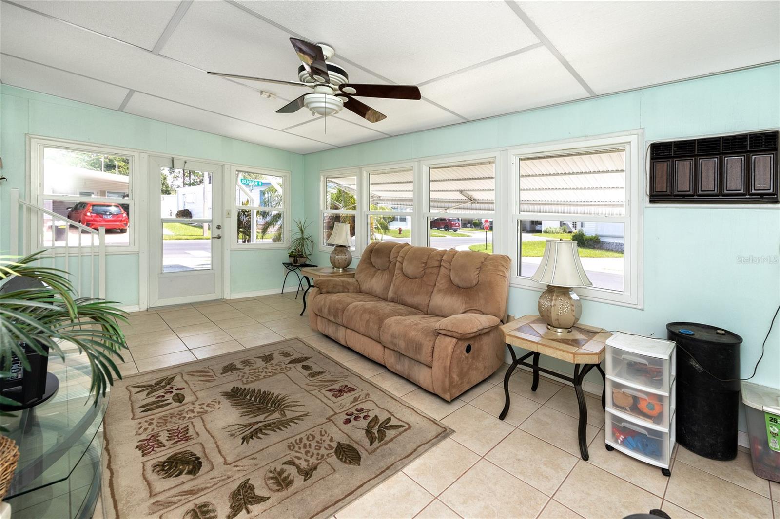 Large, bright Florida room with wall unit AC, and laundry room with storage space.