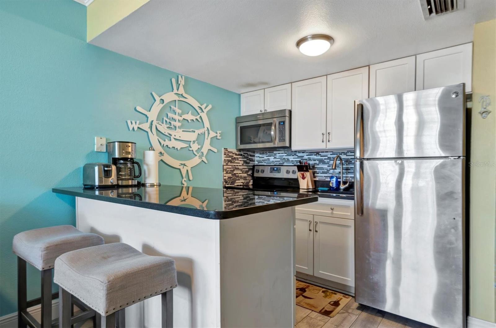 Kitchen with refrigerator, range and microwave.