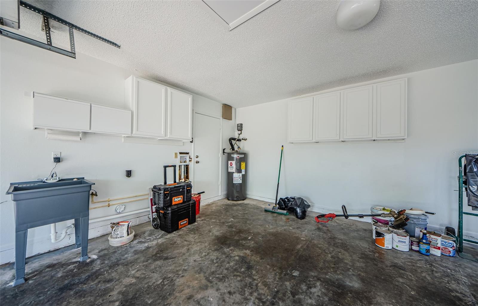 View in the Garage showing the entrance into the kitchen, the washer and dryer hookup next to the new laundry sink. More Storage!