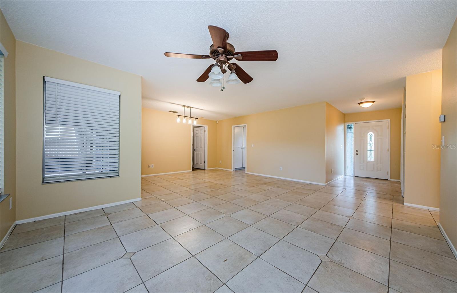 Photo is showing Entry to 2nd and 3rd Bedrooms on the near right, the Front Door to the far right, The entry to the Kitchen is center, the entry to the Primary Bedroom is to the left of kitchen entry. The window to the far left is looking out at the screened lanai.