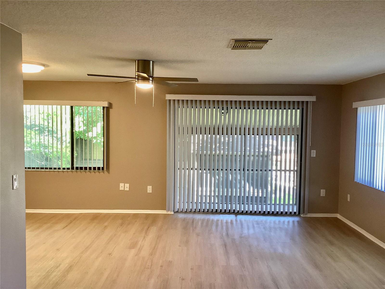 Beautiful new vinyl plank flooring. Living room with sliders leading to screened Florida room.