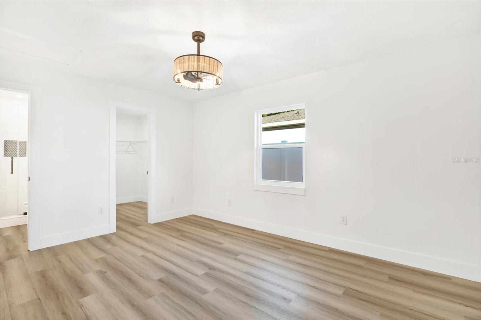 Primary bedroom with an en-suite, fandelier, and a spacious walk-in-closet