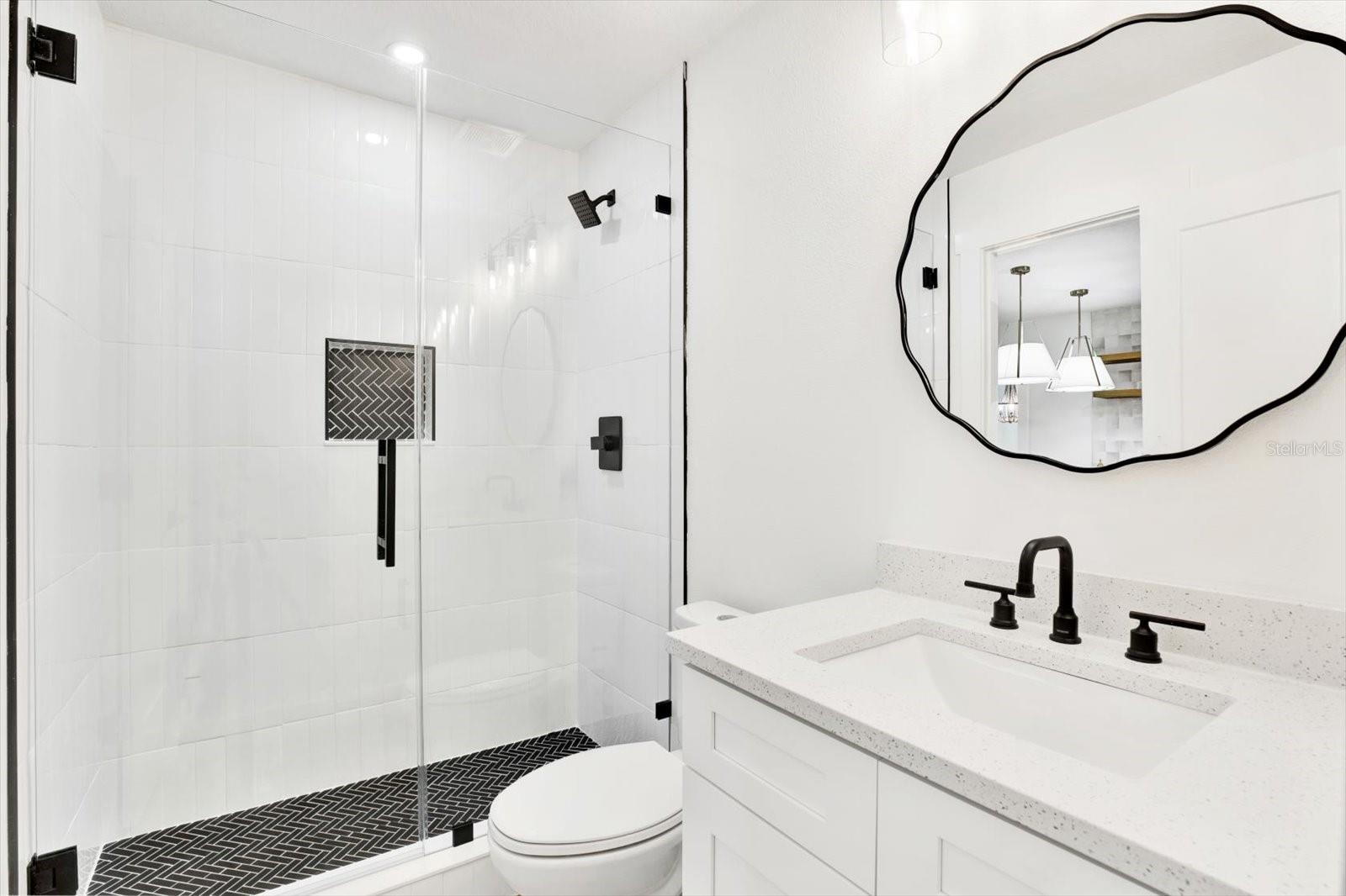 En-suite bathroom of primary bedroom with a frameless glass shower that boasts beautiful modern tones, tile, and a built-in niche