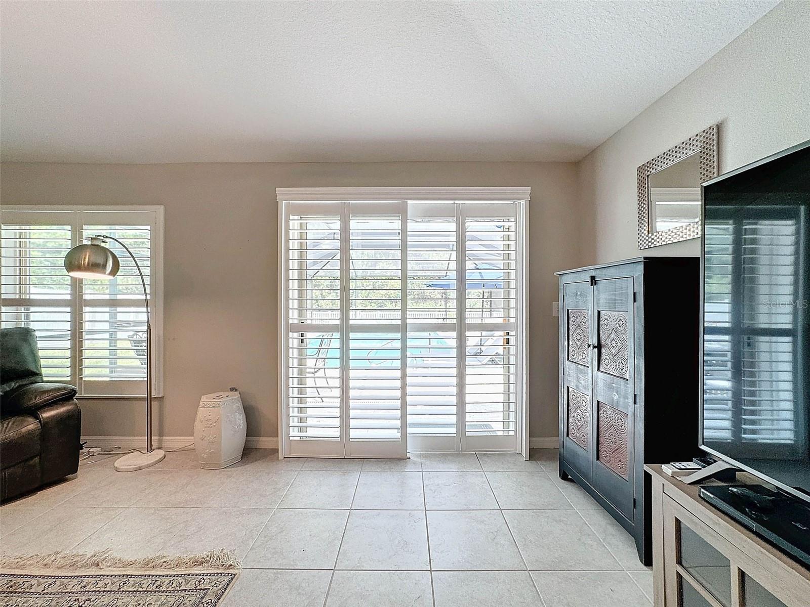 PLANTATION SHUTTERS DRESS UP THE SLIDING GLASS DOORS TO THE POOL AND LANAI