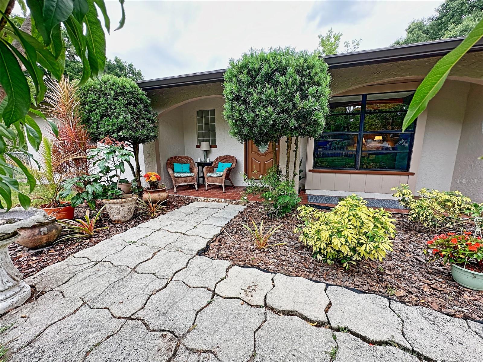 The front walk way is surrounded by peach trees.