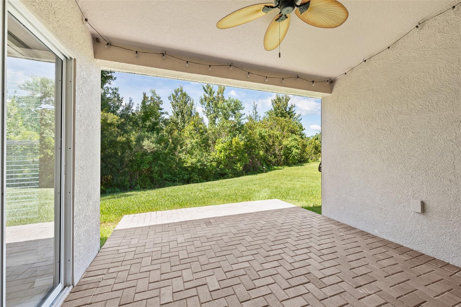 Covered extended lanai with pavers overlooking conservation