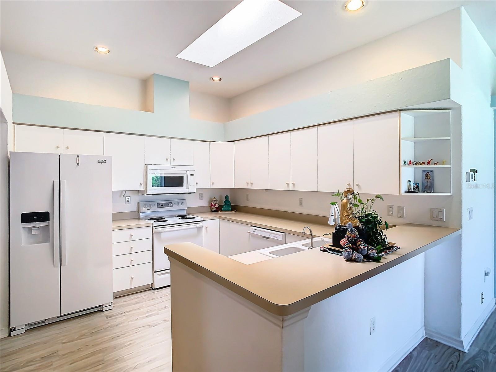 The kitchen has plenty of lighting from the recessed lights and the skylight. Flooring is laminate.